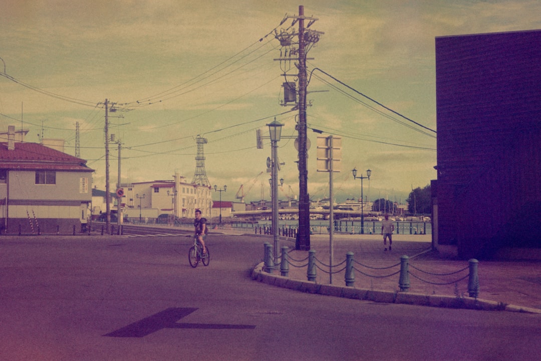 man in black jacket and blue denim jeans riding bicycle on road during daytime