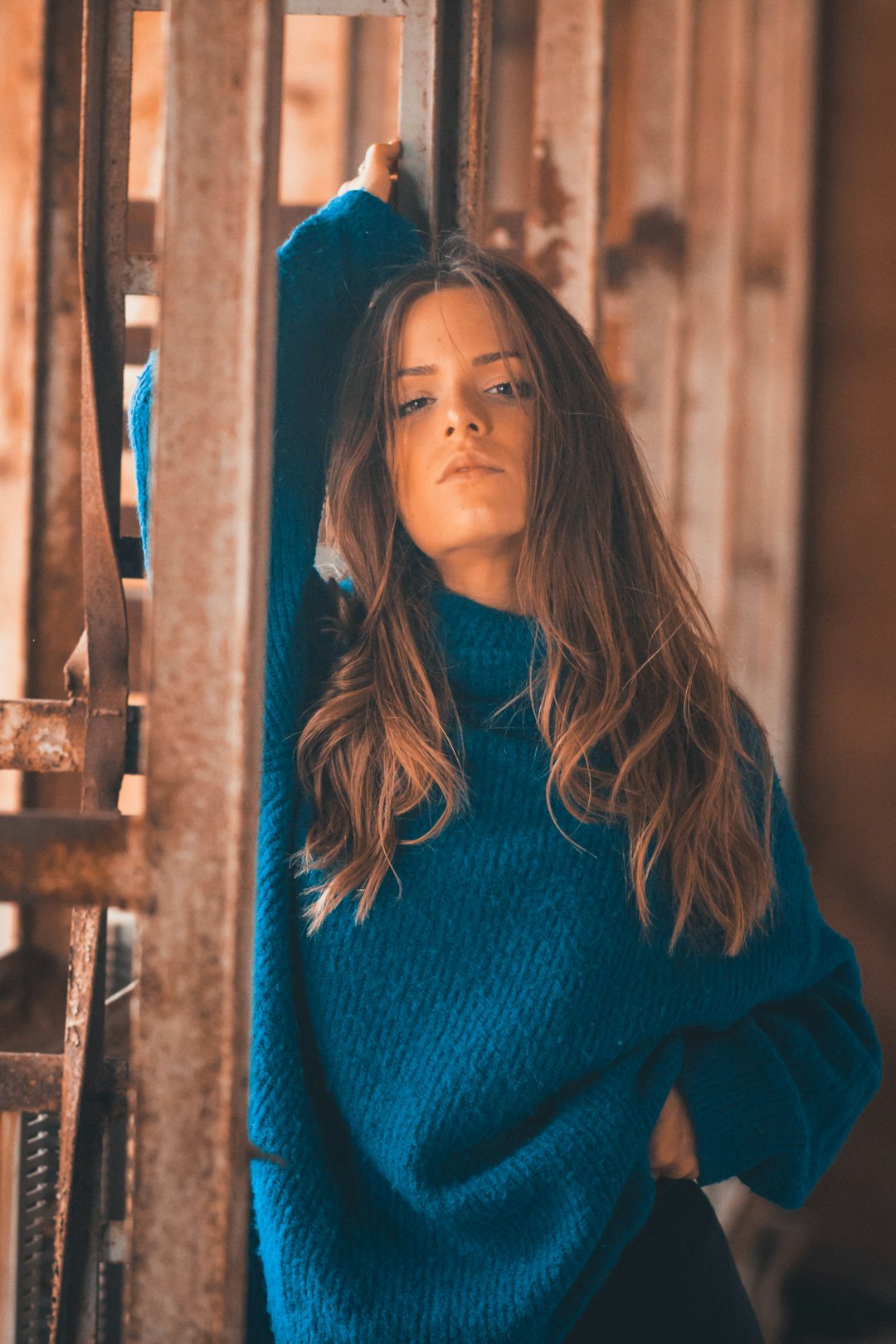 woman in red sweater standing near blue metal fence during daytime