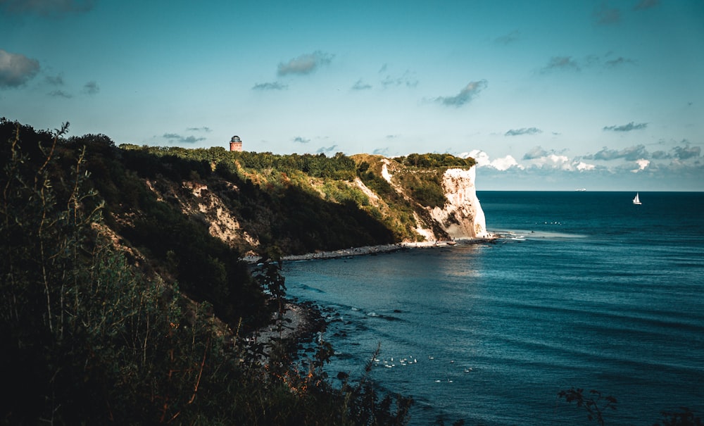 brown and green rock formation beside blue sea under blue sky during daytime