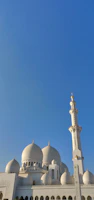 Close-up of the grand mosque Fayçal with its four tall minarets against a clear blue sky.