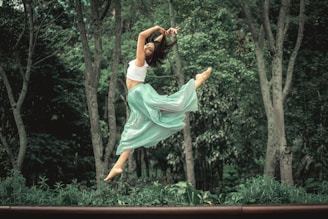 woman in white dress jumping on brown wooden fence during daytime