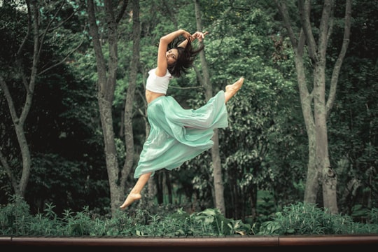 woman in white dress jumping on brown wooden fence during daytime in Bogota Colombia