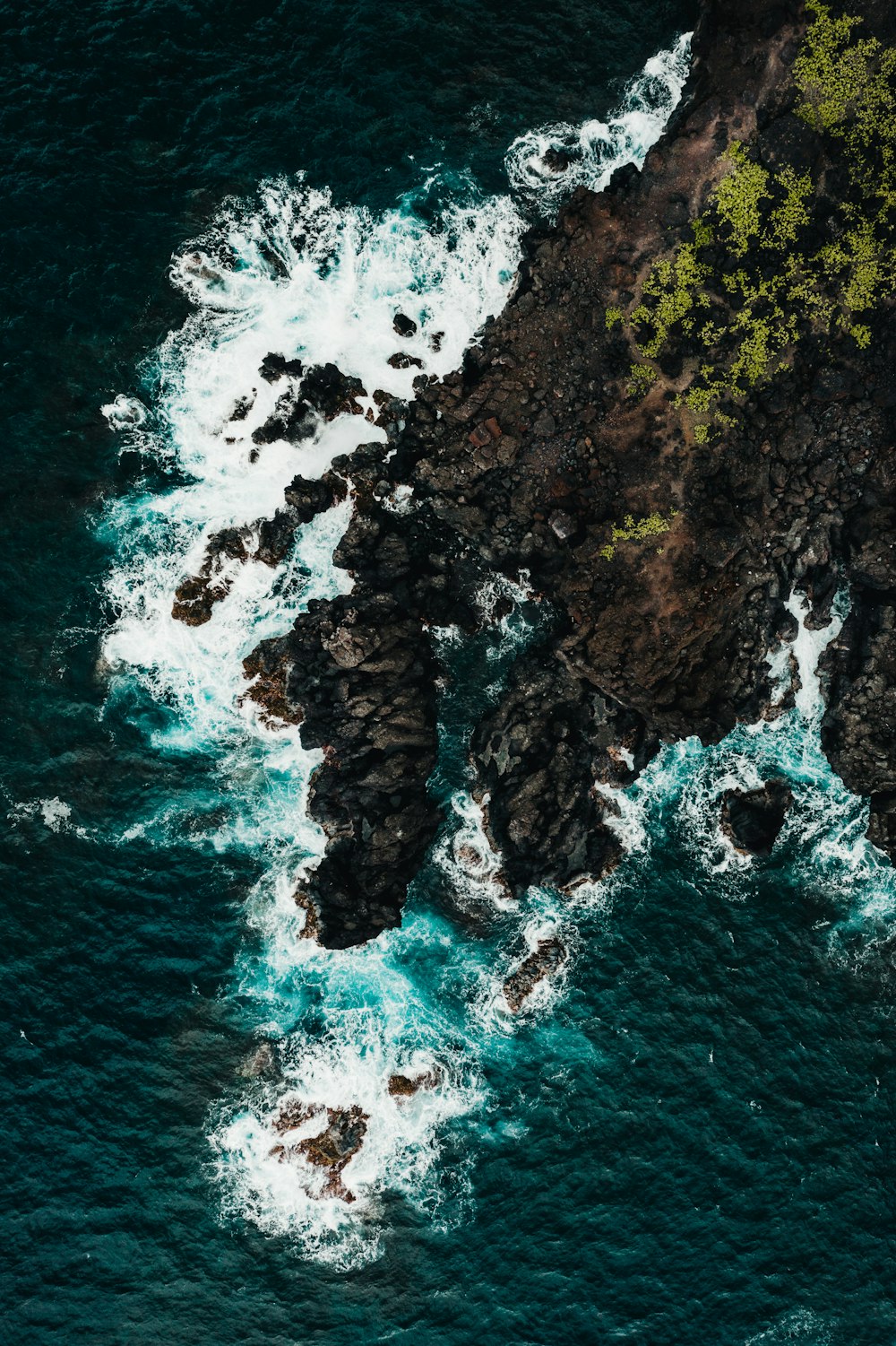 brown and green rock formation on body of water during daytime