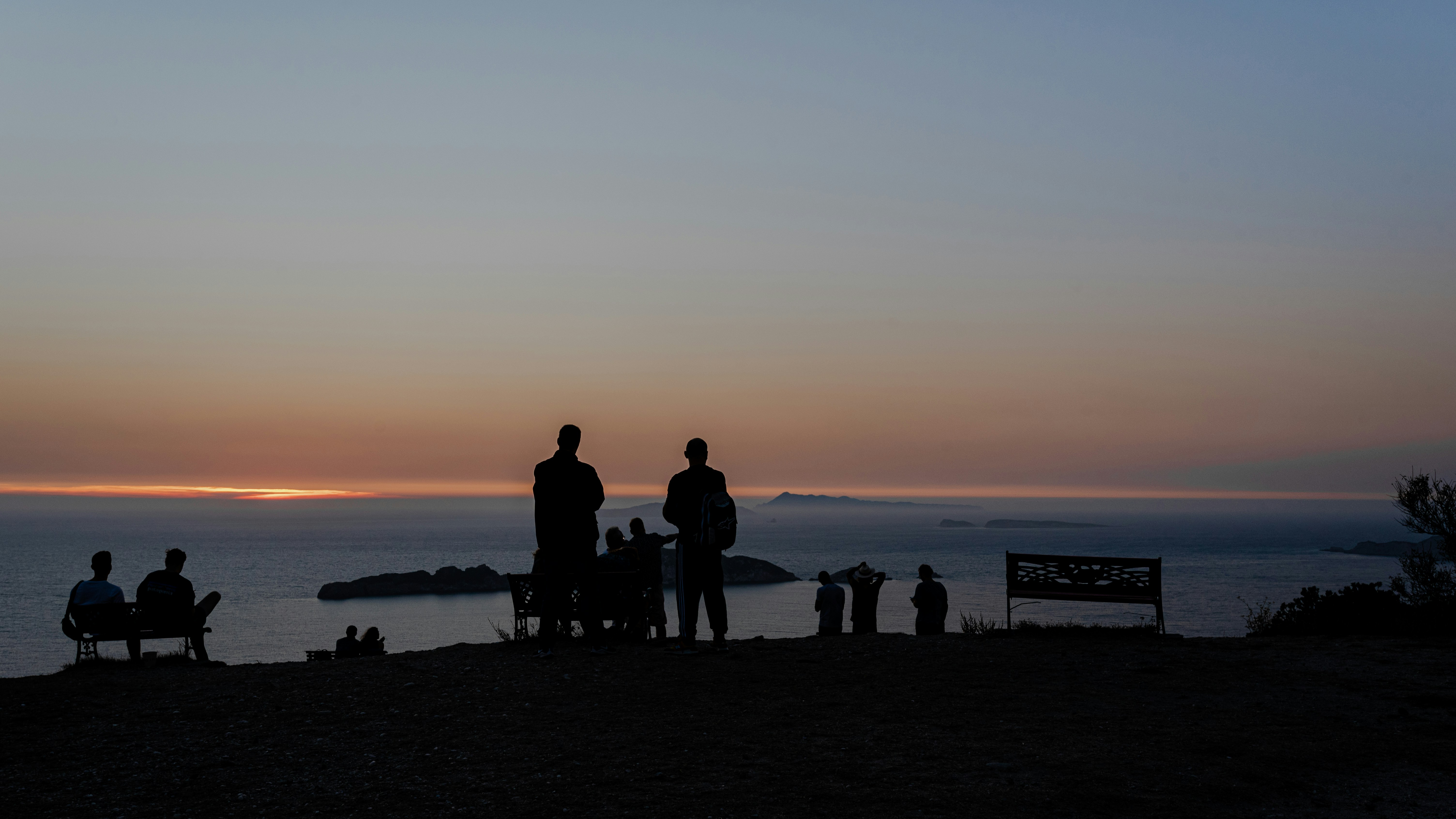 silhouette of people standing on beach during sunset