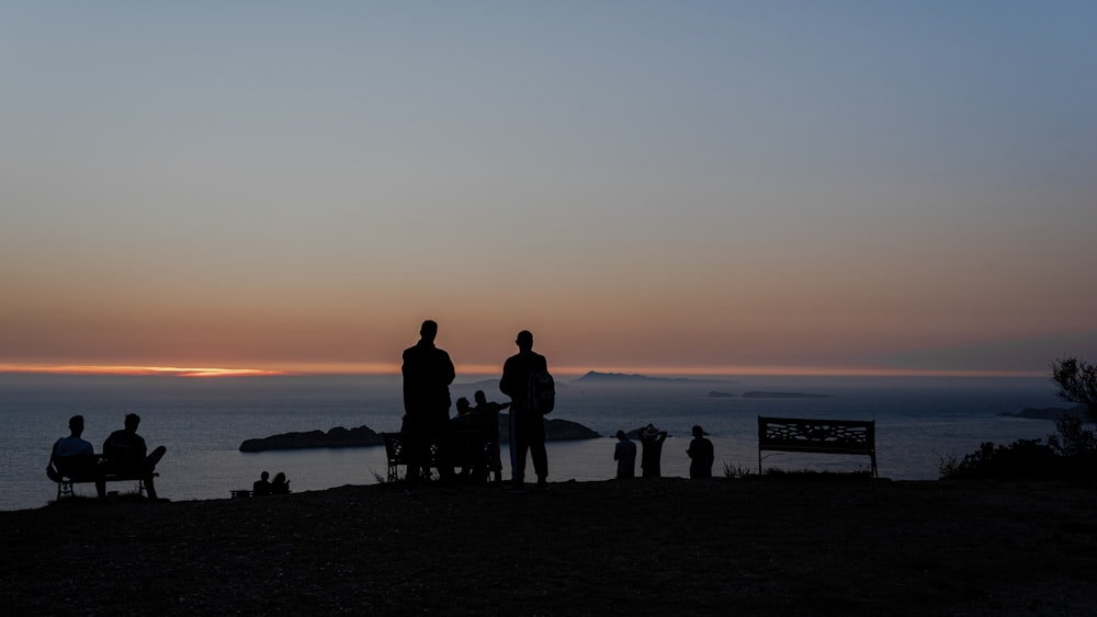 silhouette of people standing on beach during sunset