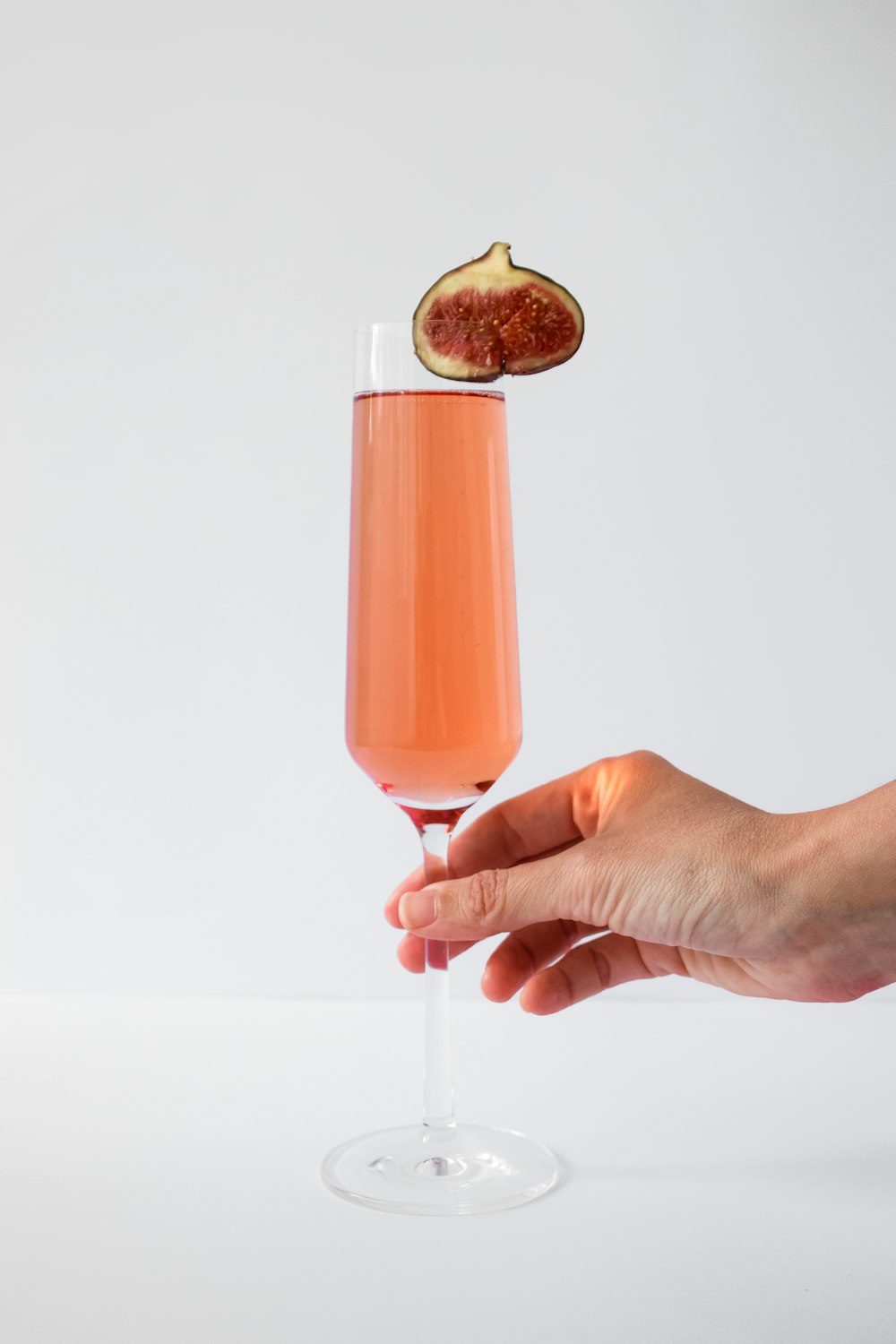 person holding clear drinking glass with orange liquid