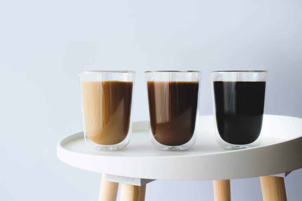 3 clear drinking glasses on white wooden table