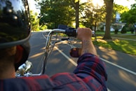 A rider wearing a helmet cruising through a tree-lined road on a sunny day.
