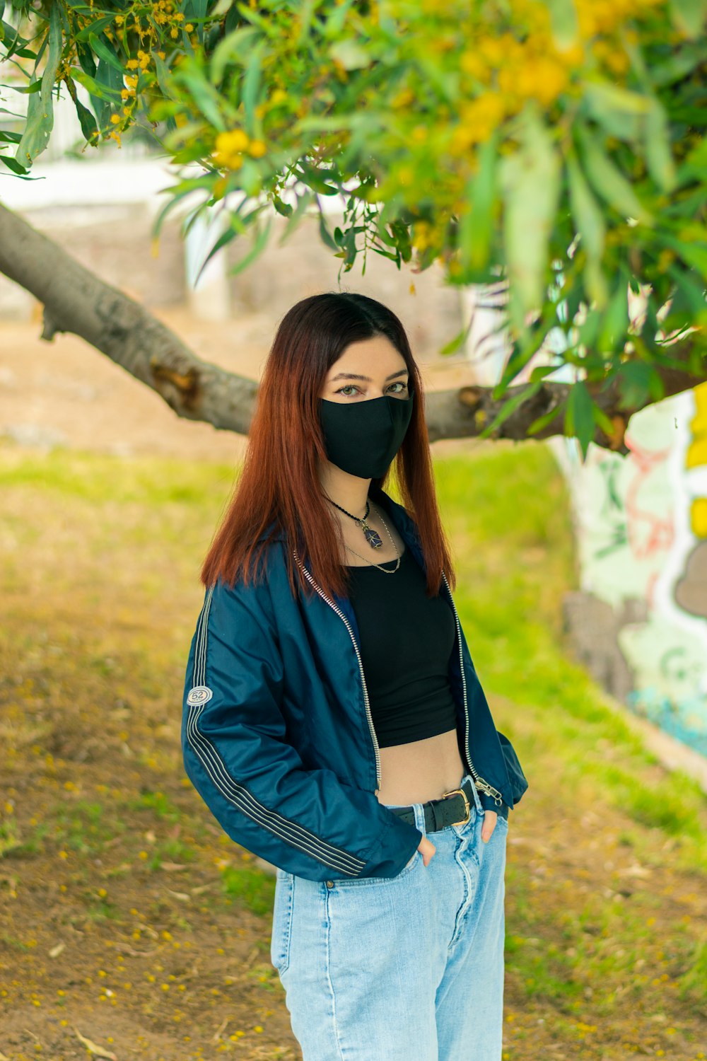 woman in black long sleeve shirt and blue denim jeans standing near green leaf tree during