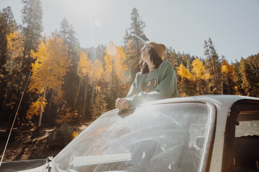 a woman sitting on top of a car talking on a cell phone