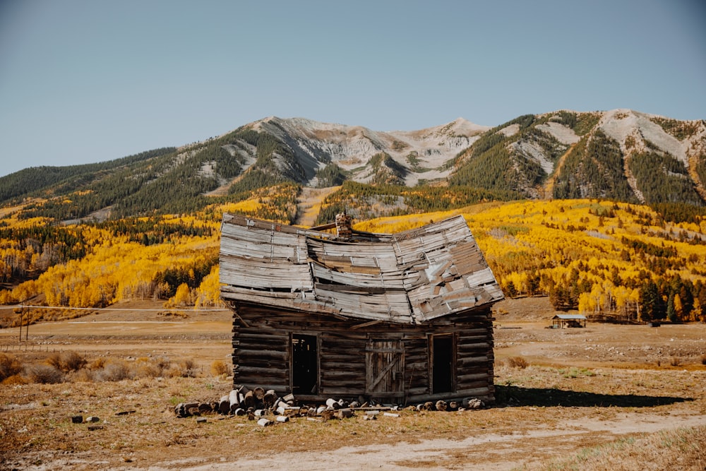 casa di legno marrone sul campo di erba marrone vicino alla montagna durante il giorno