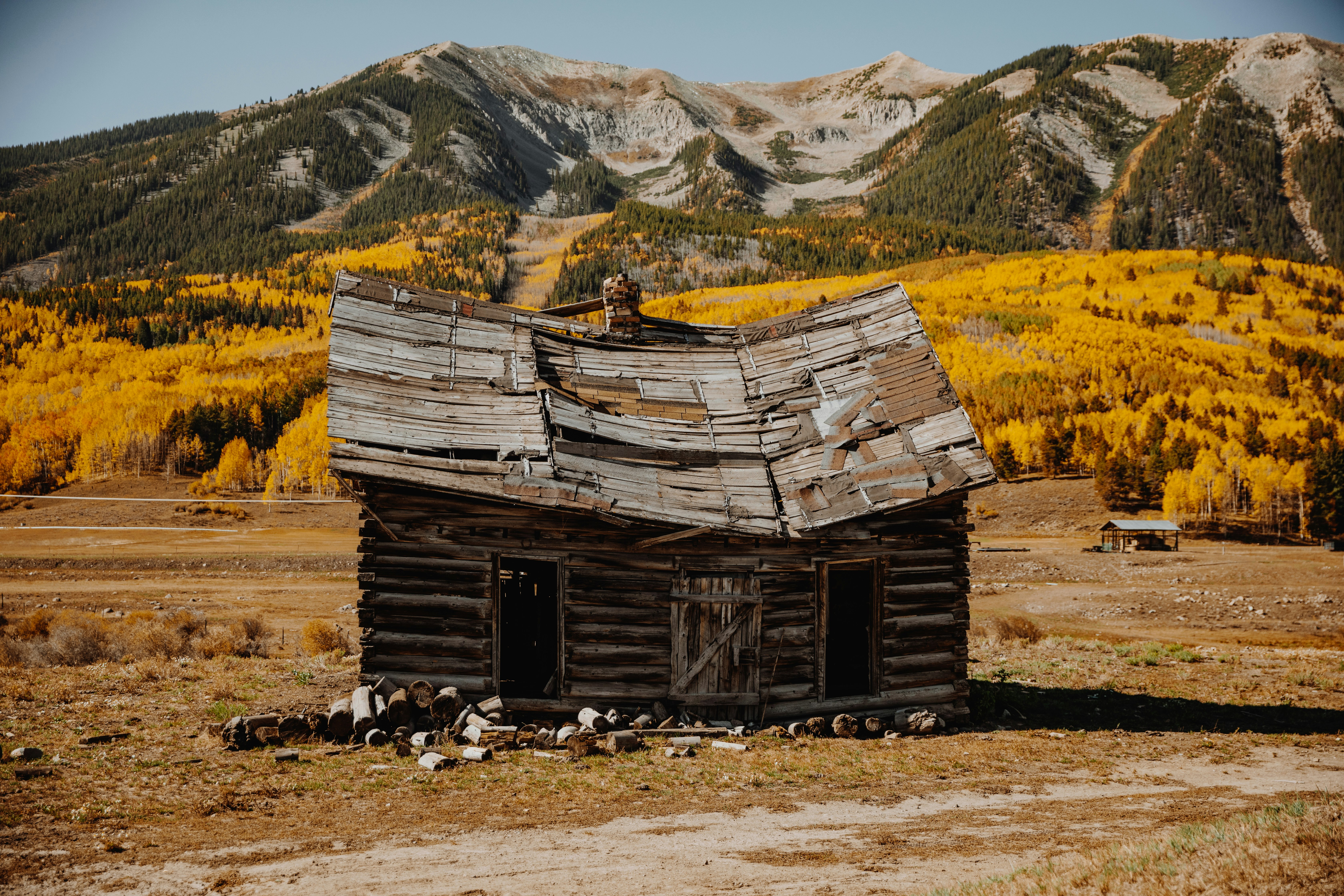 brown wooden house on brown grass field near mountain during daytime