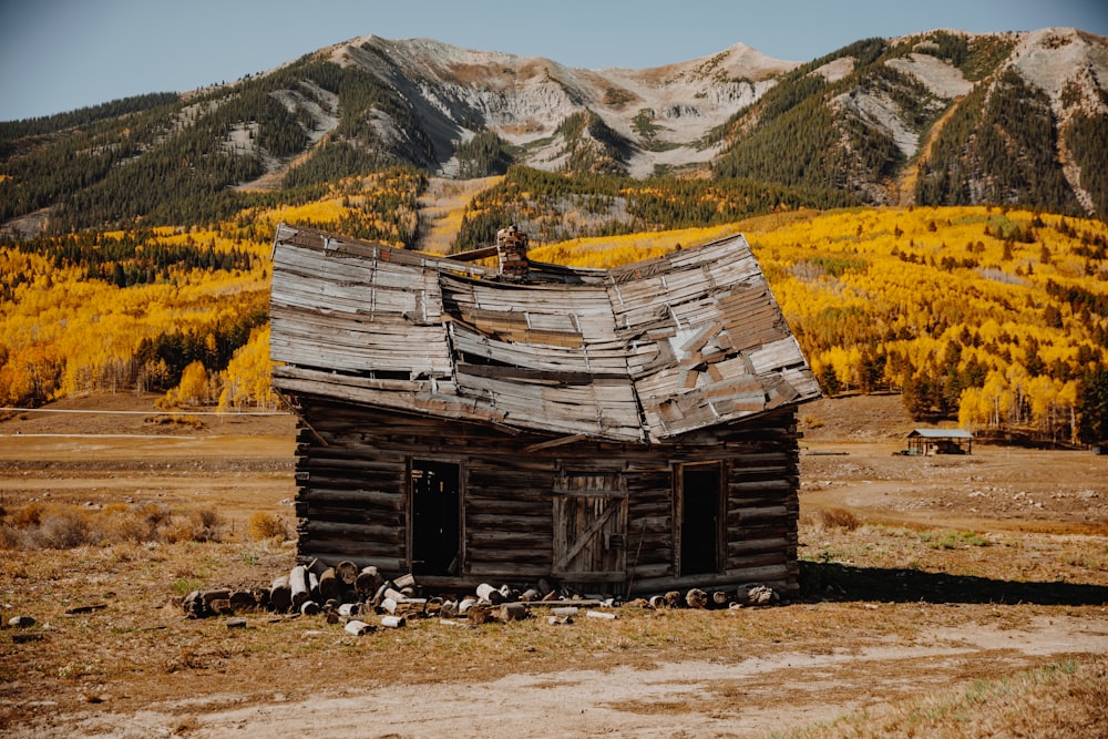 casa di legno marrone sul campo di erba marrone vicino alla montagna durante il giorno
