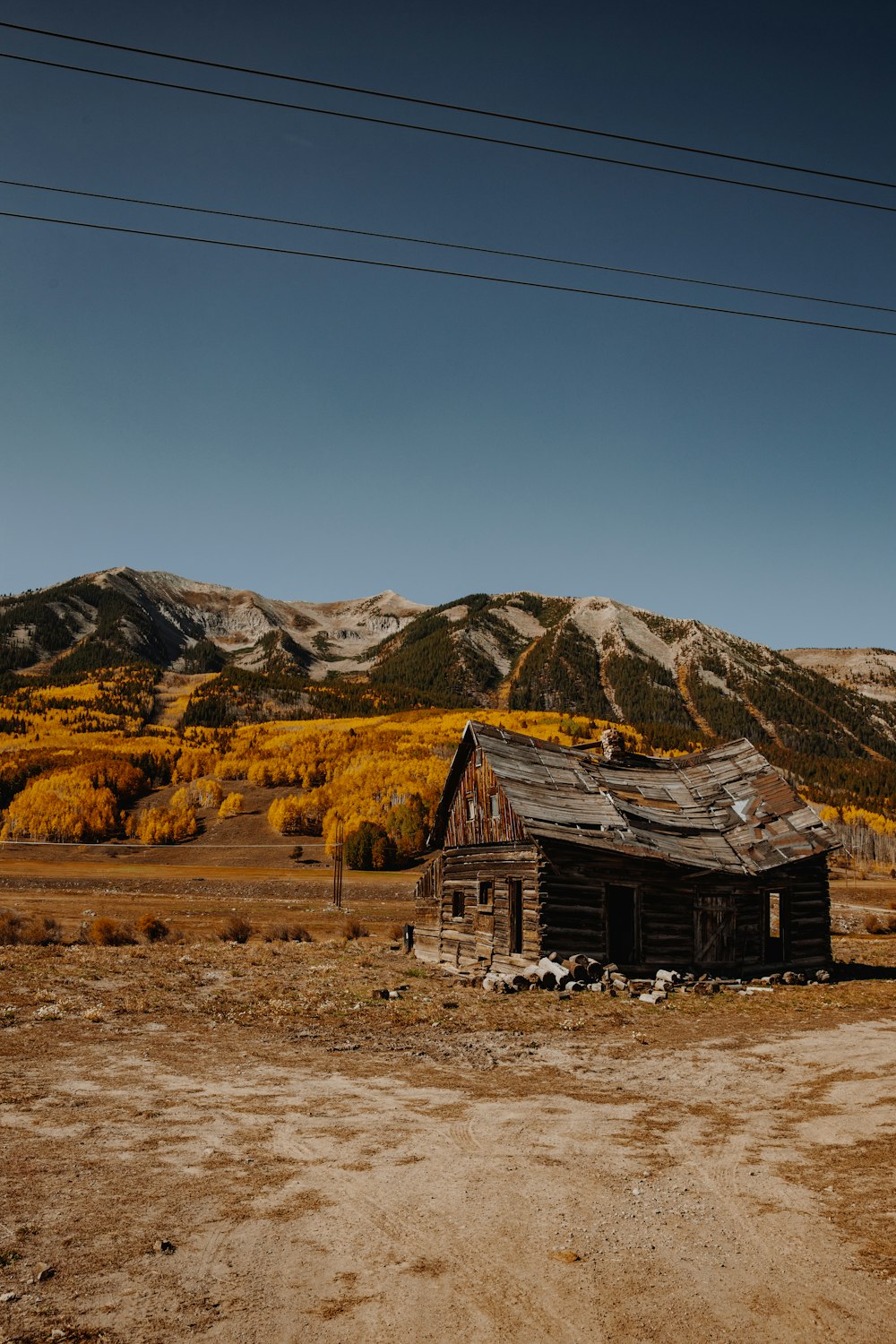 brown wooden house on brown field near brown mountains under blue sky during daytime