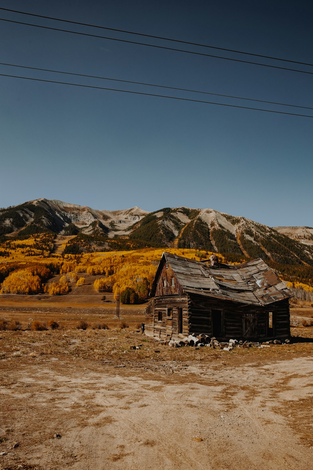 Maison en bois marron sur un champ brun près des montagnes brunes sous le ciel bleu pendant la journée