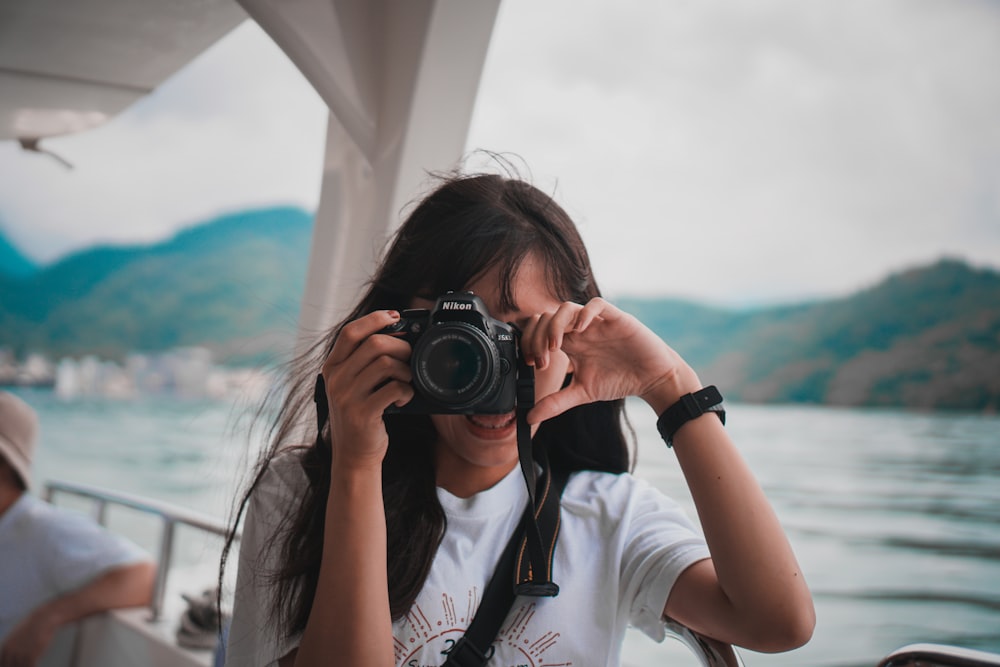 woman in white shirt holding black dslr camera