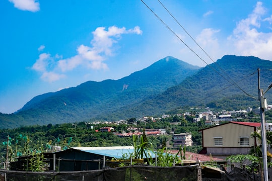 houses near mountain under blue sky during daytime in Pingtung Taiwan
