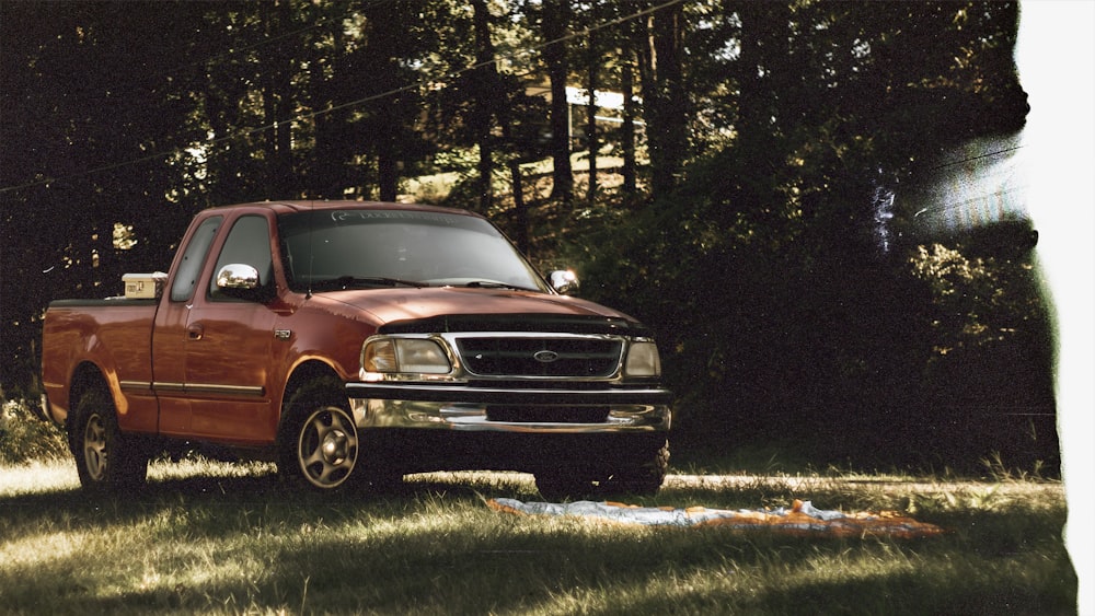 Roter Chevrolet Crew Cab Pickup Truck, der tagsüber auf grünem Rasenfeld geparkt ist