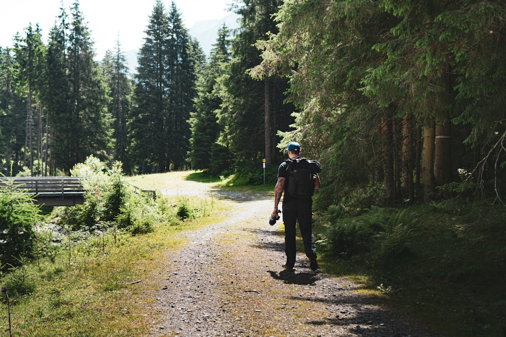 2 hommes marchant sur un chemin de terre entre des arbres verts pendant la journée