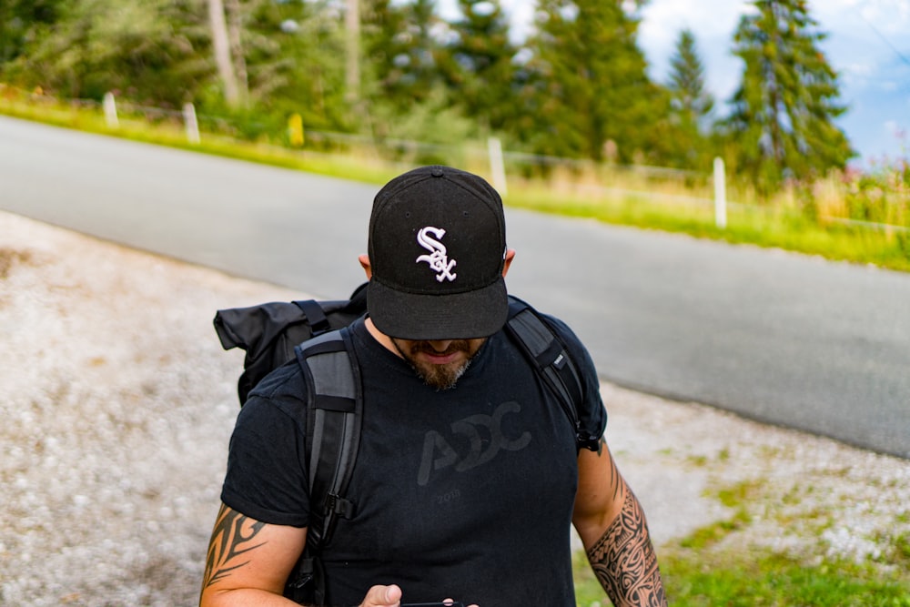 man in black nike backpack and black backpack standing on road during daytime