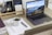 Close-up of hands organizing paperwork on a wooden desk with a laptop and stationery.