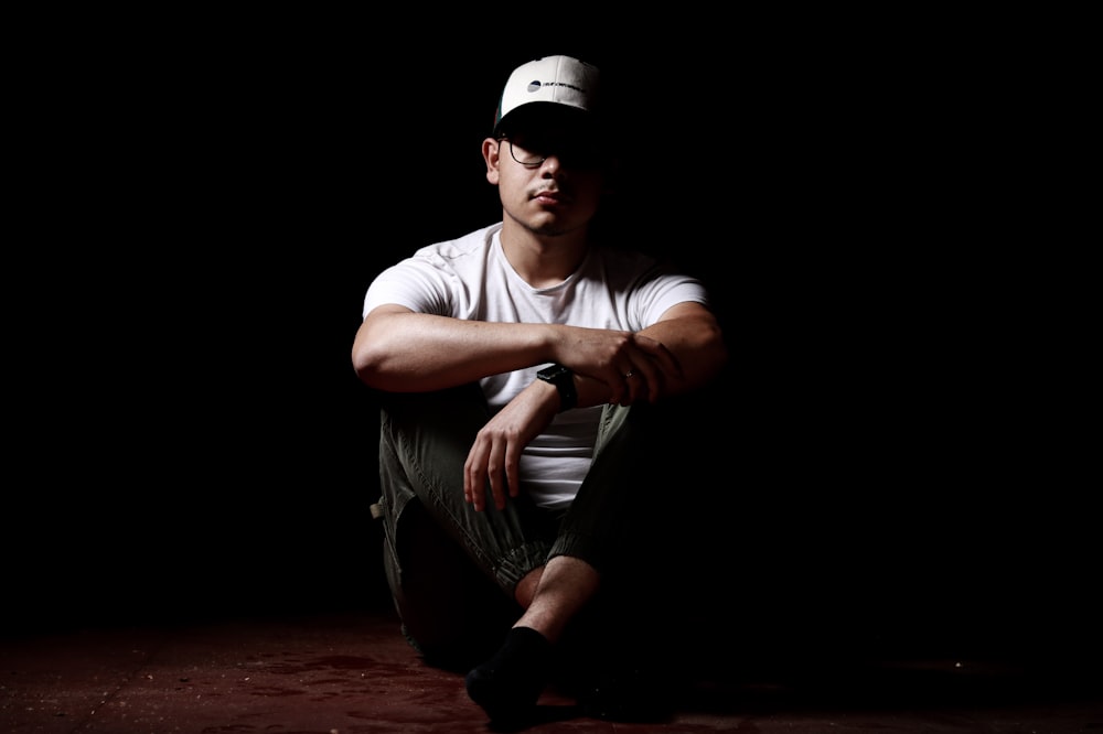 man in white crew neck t-shirt and brown pants sitting on floor