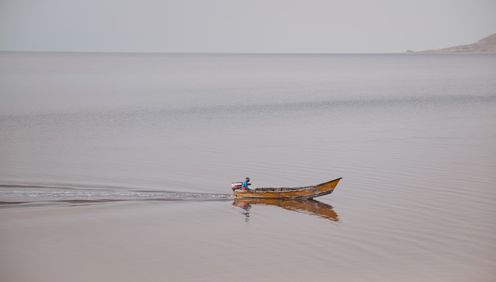 man in brown boat on sea during daytime