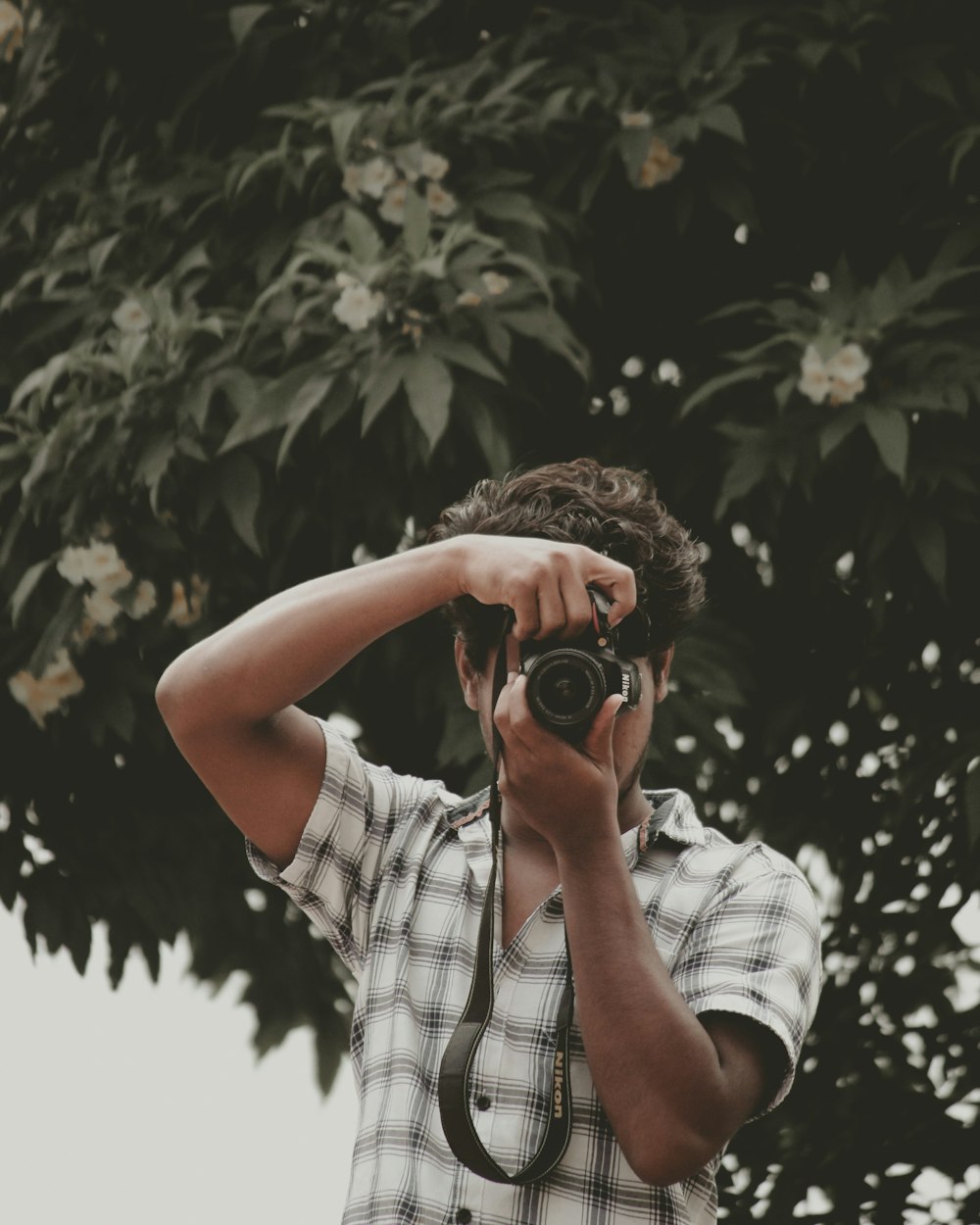 man in white and black plaid button up t-shirt holding camera