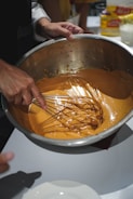 Hands mixing colorful cake batter in a glass bowl