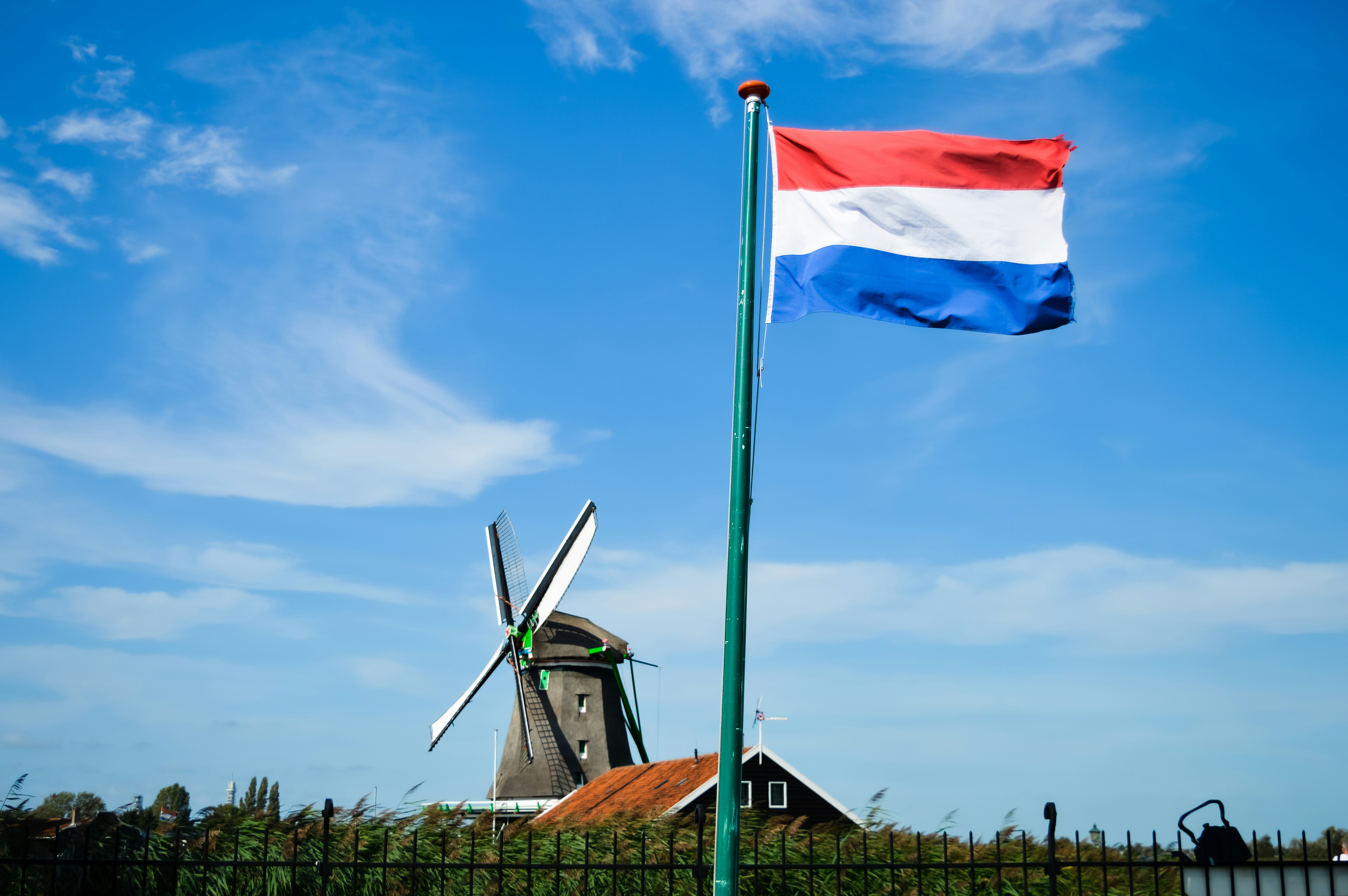 Netherlands flag-waving close in Zaanse Schans, one of the Netherlands postcards due to the historical windmills