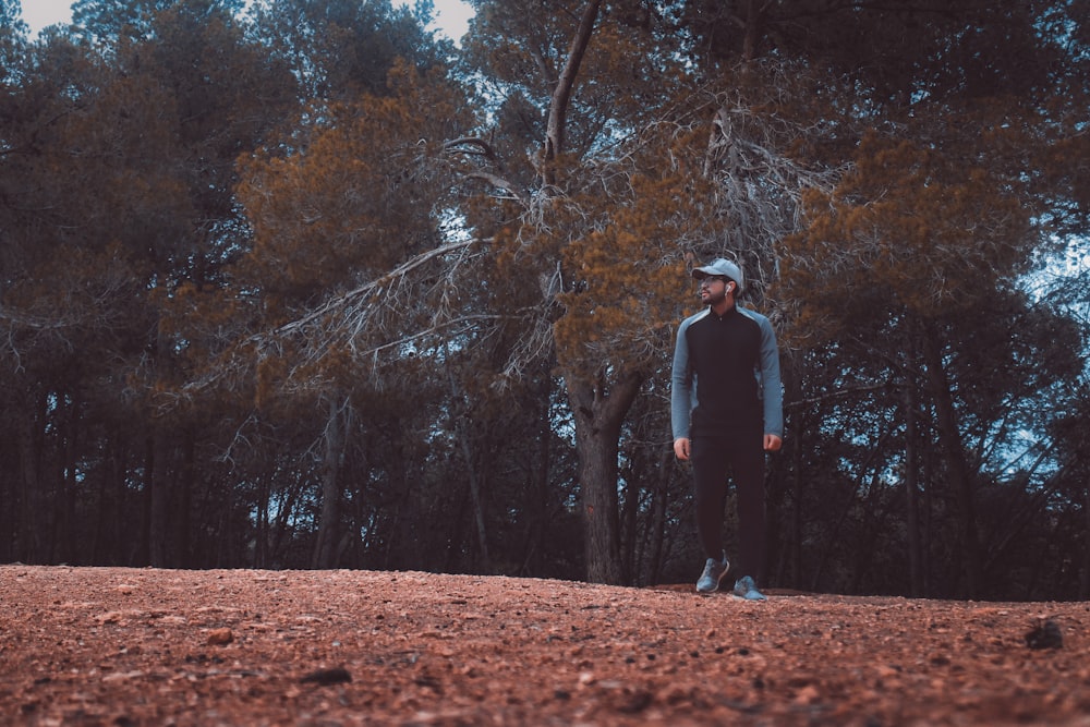 man in gray jacket standing on brown dirt road