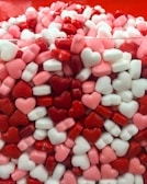 A collection of colorful heart bags displayed on a minimalist white shelf.
