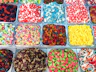 Trays of colorful bulk gummy candies, including gummy bears, sour worms and cola bottles, in a self-serve candy store display