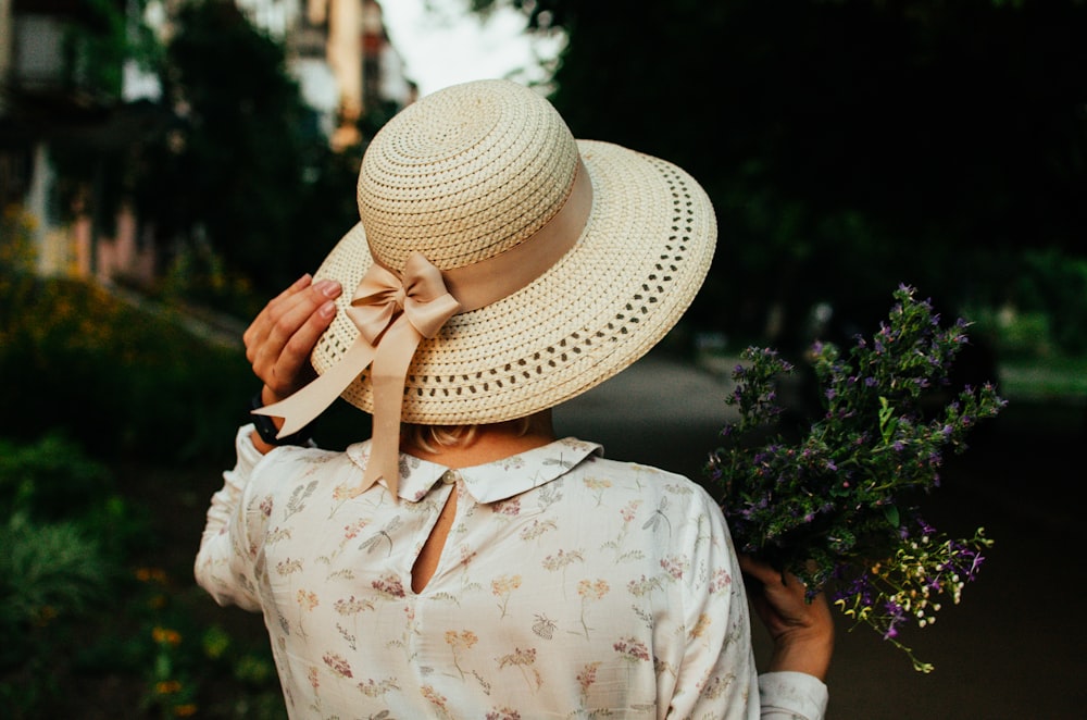 person in white and yellow floral button up shirt wearing white sun hat