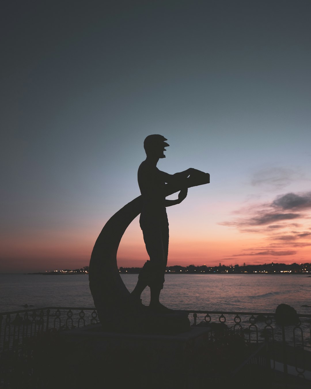 silhouette of man holding surfboard during sunset