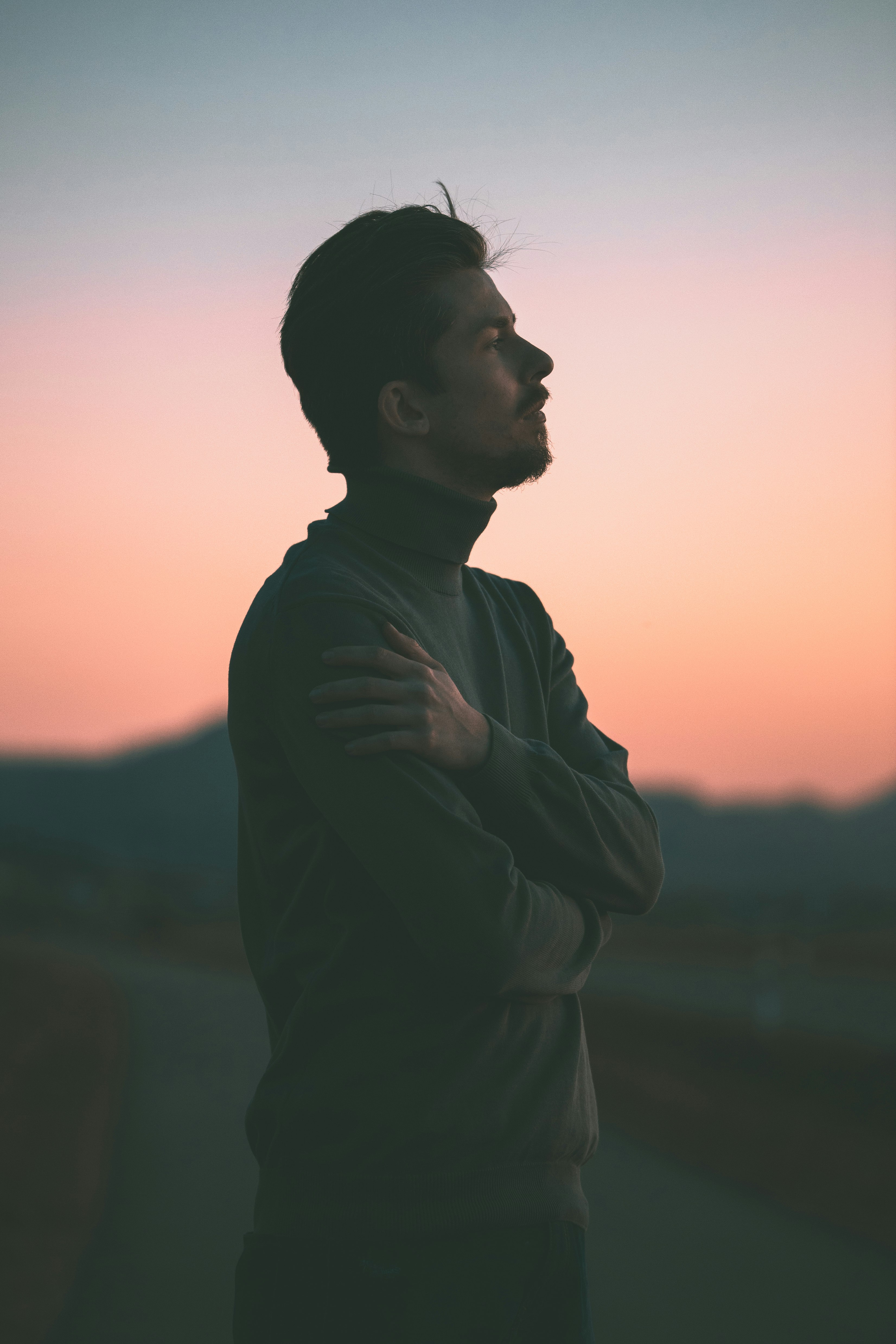man in gray long sleeve shirt standing during sunset