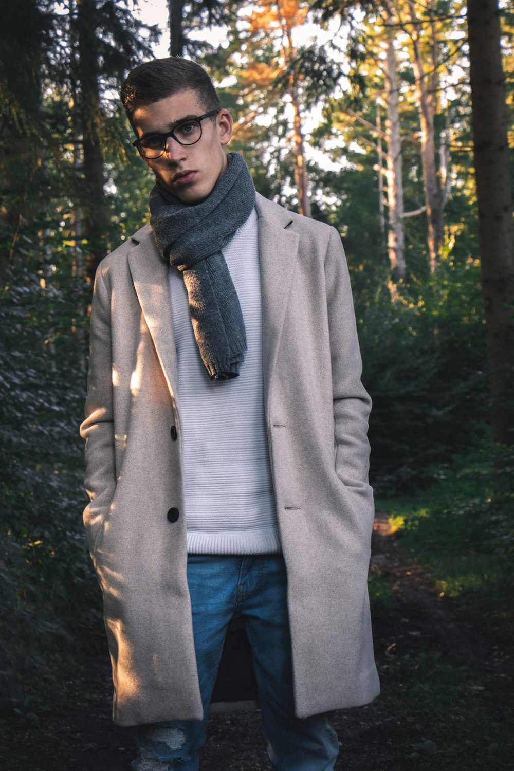 man in gray coat standing in forest during daytime