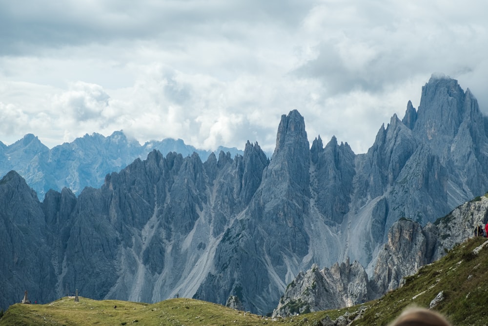 green grass field near mountain under white clouds during daytime