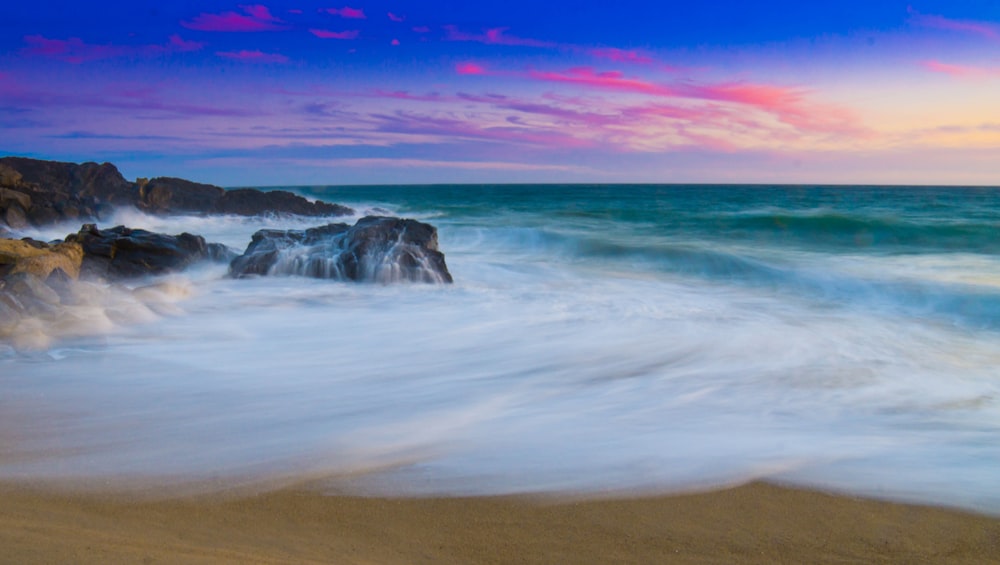 ocean waves crashing on shore during sunset