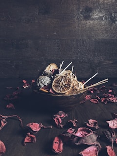 A rustic wooden bowl filled with male face scrub next to fresh eucalyptus leaves.