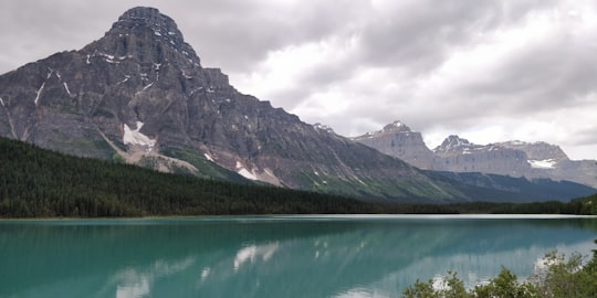 green lake near mountain under cloudy sky during daytime in Mount Chephren Canada