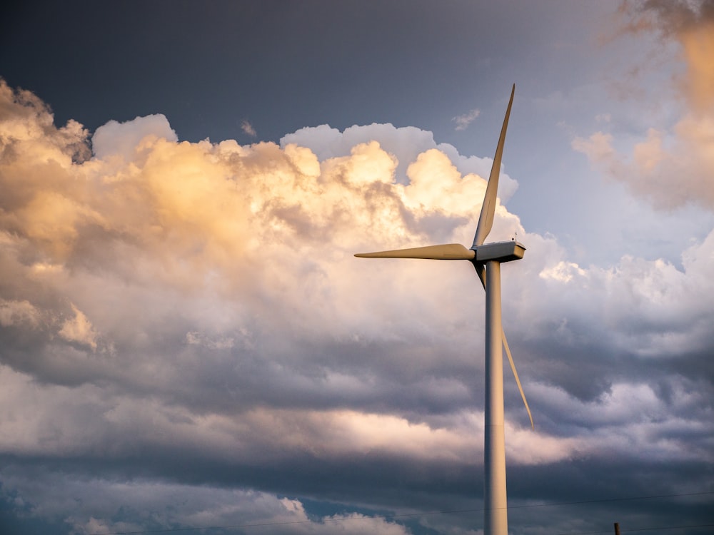 white wind turbine under white clouds and blue sky during daytime