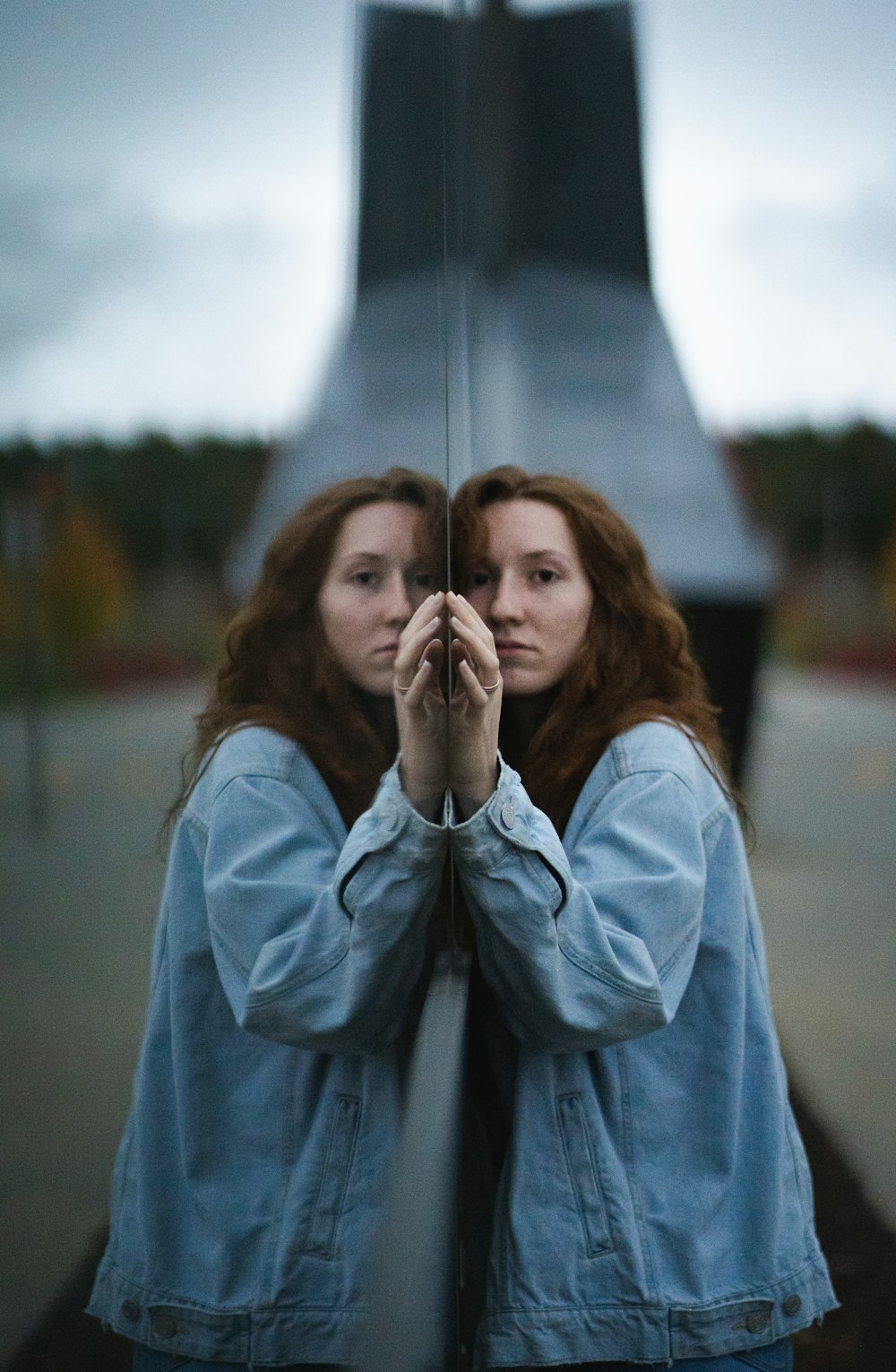 woman in blue denim jacket covering her face with her hand