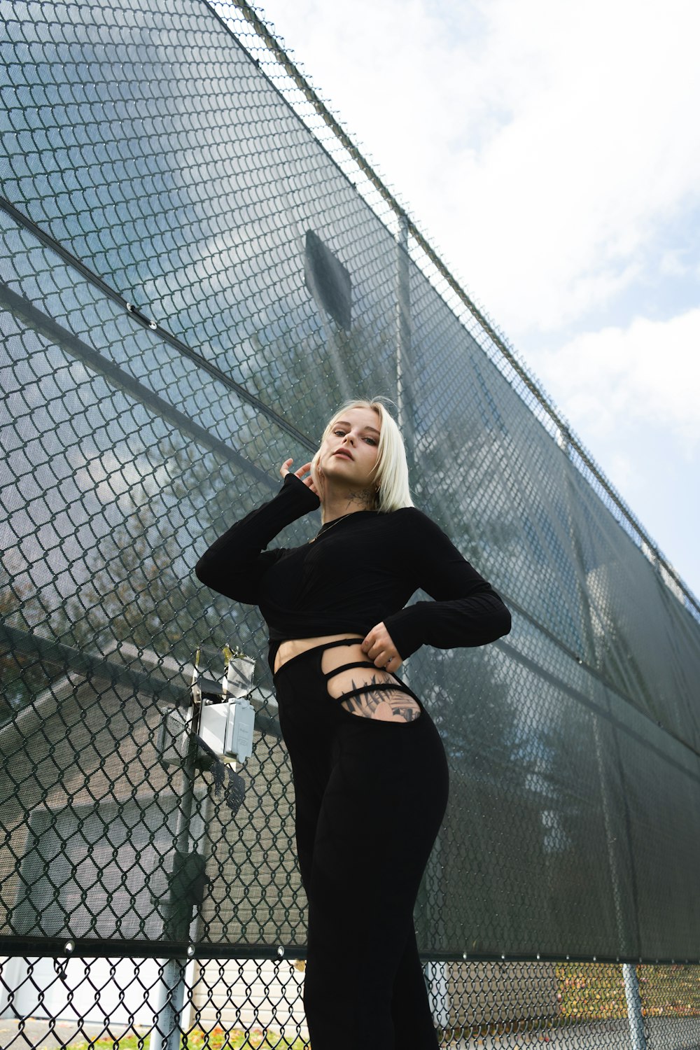 woman in black long sleeve shirt standing beside gray metal fence during daytime