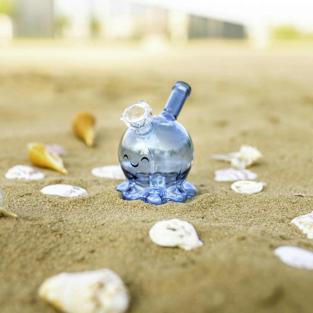 Botella de vidrio azul sobre arena marrón