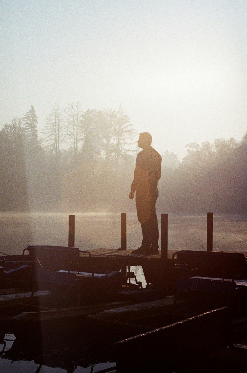 silhouette of man standing on wooden dock during daytime