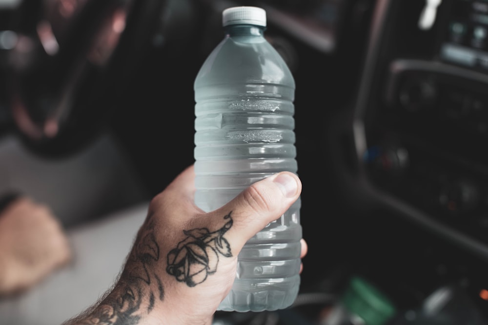 Persona sosteniendo una botella de plástico transparente