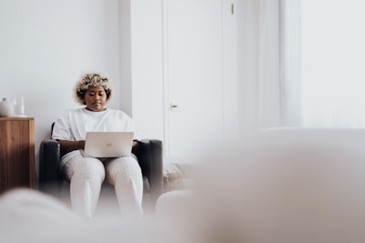 woman in white long sleeve shirt sitting on black sofa chair