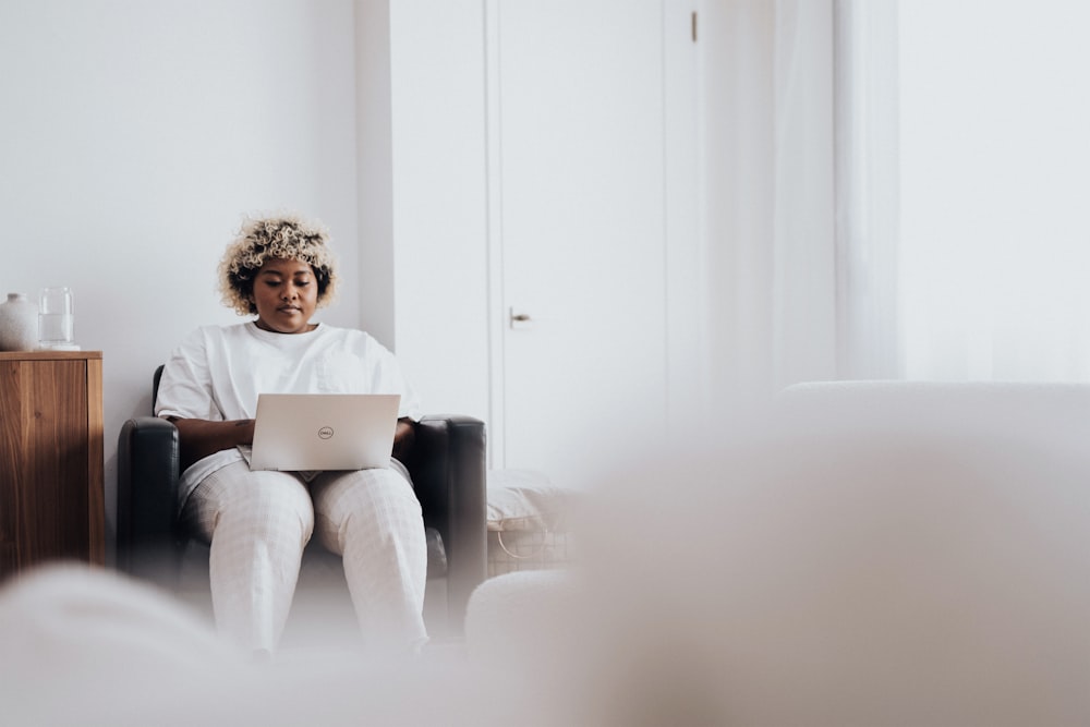 woman in white long sleeve shirt sitting on black sofa chair