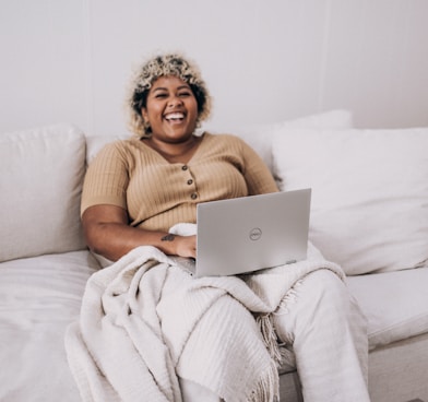 woman in brown sweater sitting on white couch